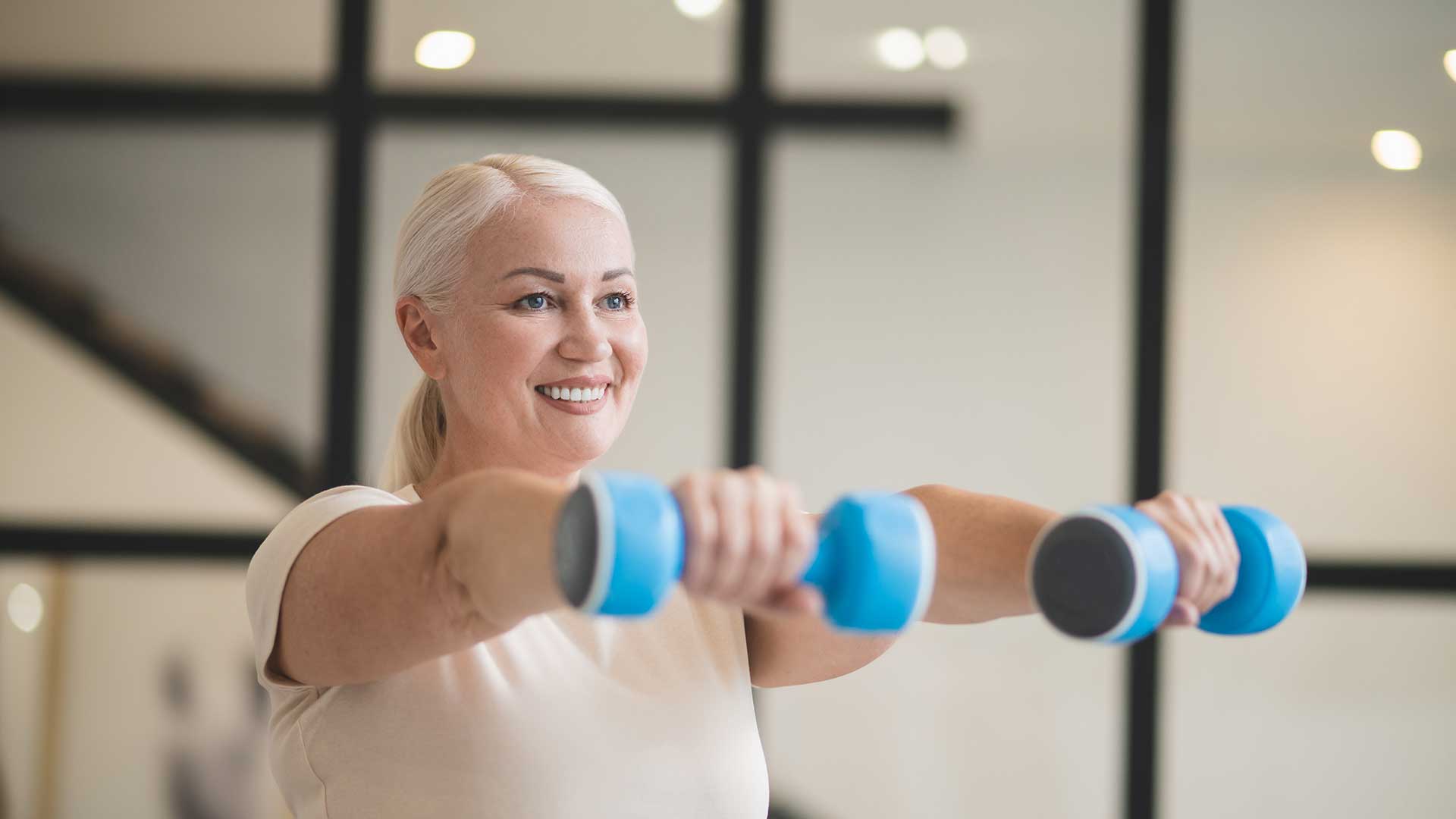 Woman exercising with dumbbells Smiling woman using dumbbells during a resistance training exercise